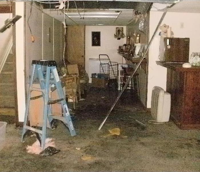 Dirty smoke residues and damaged furniture in the basement of a home.