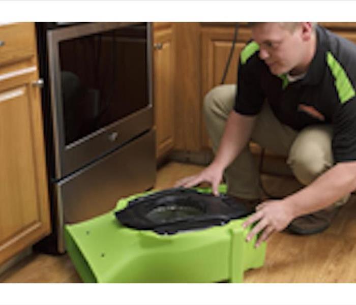 A SERVPRO professional using equipment to dry up water in a customer's kitchen.